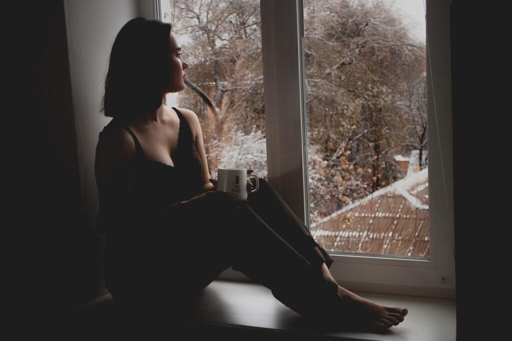 girl, window, sit, sitting, wait, waiting, by the window, looking out, cup, mug, indoors, woman, model, sad, person, brunette, female, young woman, thinking, sad girl, lady, depression, melancholy, tired