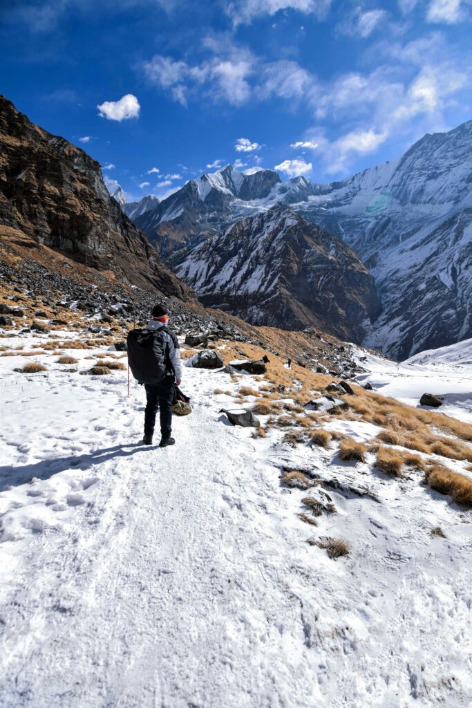 A lone hiker traverses a snowy mountain path with breathtaking views.
